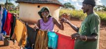 Ulita Mutambo’s husband Muchineripi Sibanda helps her hang up laundry outside their home in Ture Village, Zvishevane region, Zimbabwe. Aurelie Marrier d'Unienville / Oxfam