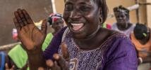 Isatu Kamara, 40, leads oxfam volunteers and the community in a song to thank Oxfam for their intervention during the Ebola outbreak. Sierra Leone, April 2015. Photo:Tommy Trenchard/Oxfam