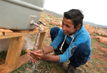 A resident of Btedai ITS (Informal tented settlement) washes his hands with water from an Oxfam provided water tank. Credit: Adrian Hartrick/Oxfam