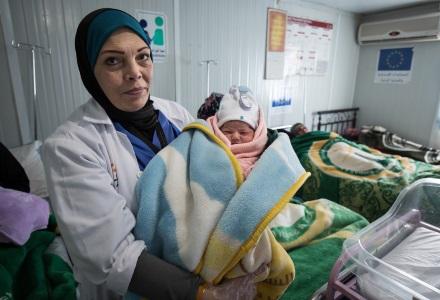 A doctor holds a new born baby in Za'atari camp, Jordan